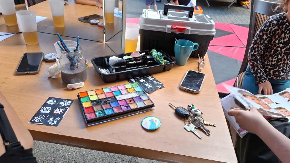 Auf dem Tisch sind Werkzeuge und Farben, mit denen Kinder geschminkt wurden